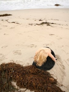 jena-ardell-young-woman-wearing-a-dress-alone-on-an-empty-beach-near-the-sea